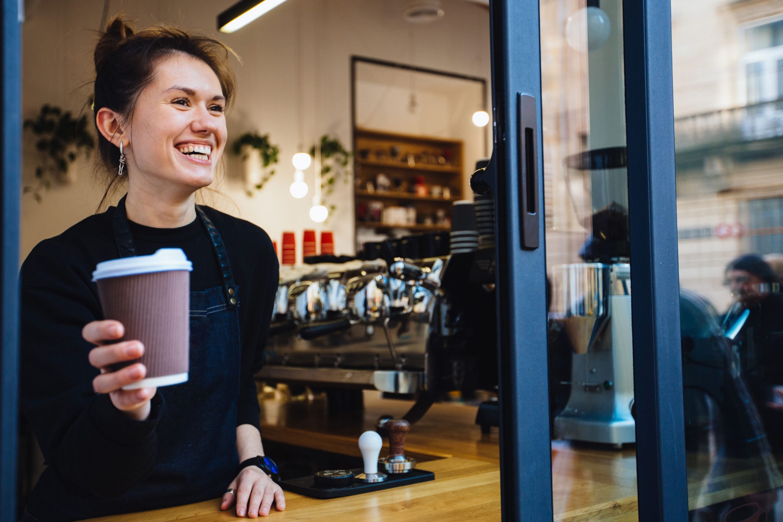 barista serving coffee at takeout window scaled